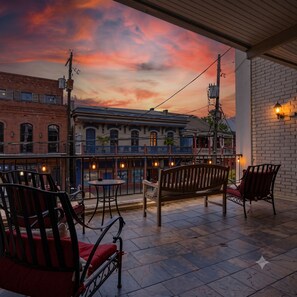 A terrace with outdoor seating, a view of a building with a blue facade, and a sunset sky. - Stylish private 1BR on Frenchmen Street with shared pool, and easy walk to the French Quarter. (New Orleans)