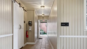 A hallway with a stone floor, white walls, a fire extinguisher, and a sign indicating the Pool & Spa area. - Elegant 2BR on Frenchmen Street with shared pool, hot tub, and easy walk to the French Quarter. (New Orleans)