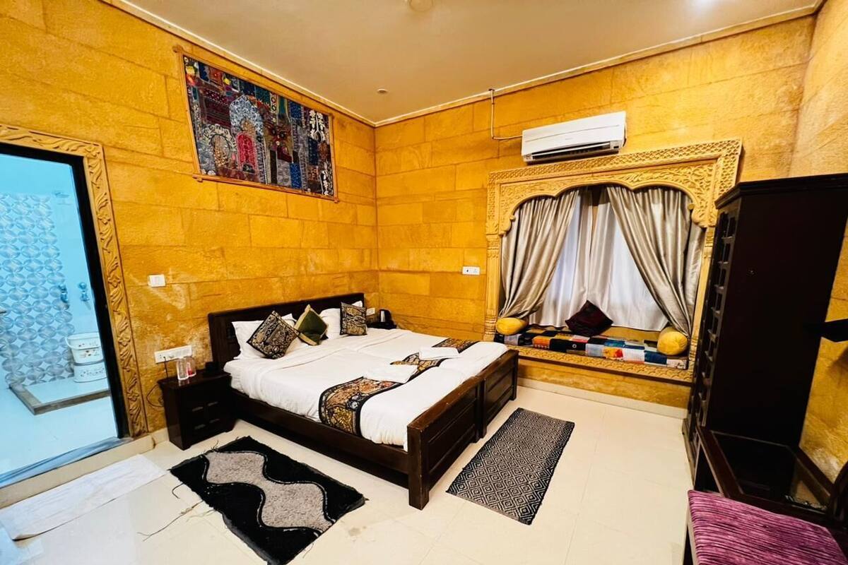 A bedroom with a bed, nightstands, a wardrobe, a window with curtains, and a wall-mounted air conditioner.