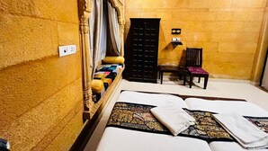 A room with a bed, a chair, a wardrobe, and a small table. - Hotel Unique Heritage  (Jaisalmer)