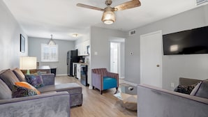 A modern living room with a sofa, armchair, and a dining area with a table and chairs. - Stylish 2BR on Frenchmen Street with shared pool, hot tub, and easy walk to the French Quarter. (New Orleans)