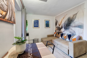A modern living room with a sofa, a coffee table, and artwork on the walls. - Museum View Holiday Home in the Historic Center (Sassello)