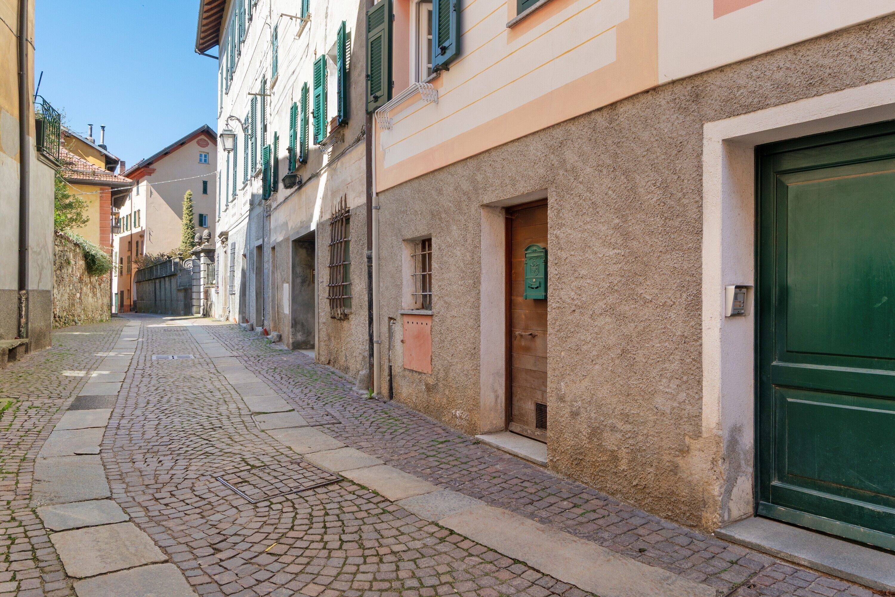 A narrow cobblestone street lined with buildings, featuring a green door on the right.