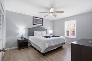 A bedroom with a bed, two bedside tables, a ceiling fan, a window with blinds, and a framed picture on the wall. - Modern 2BR near Frenchmen Street with shared pool, and easy walk to the French Quarter. (New Orleans)
