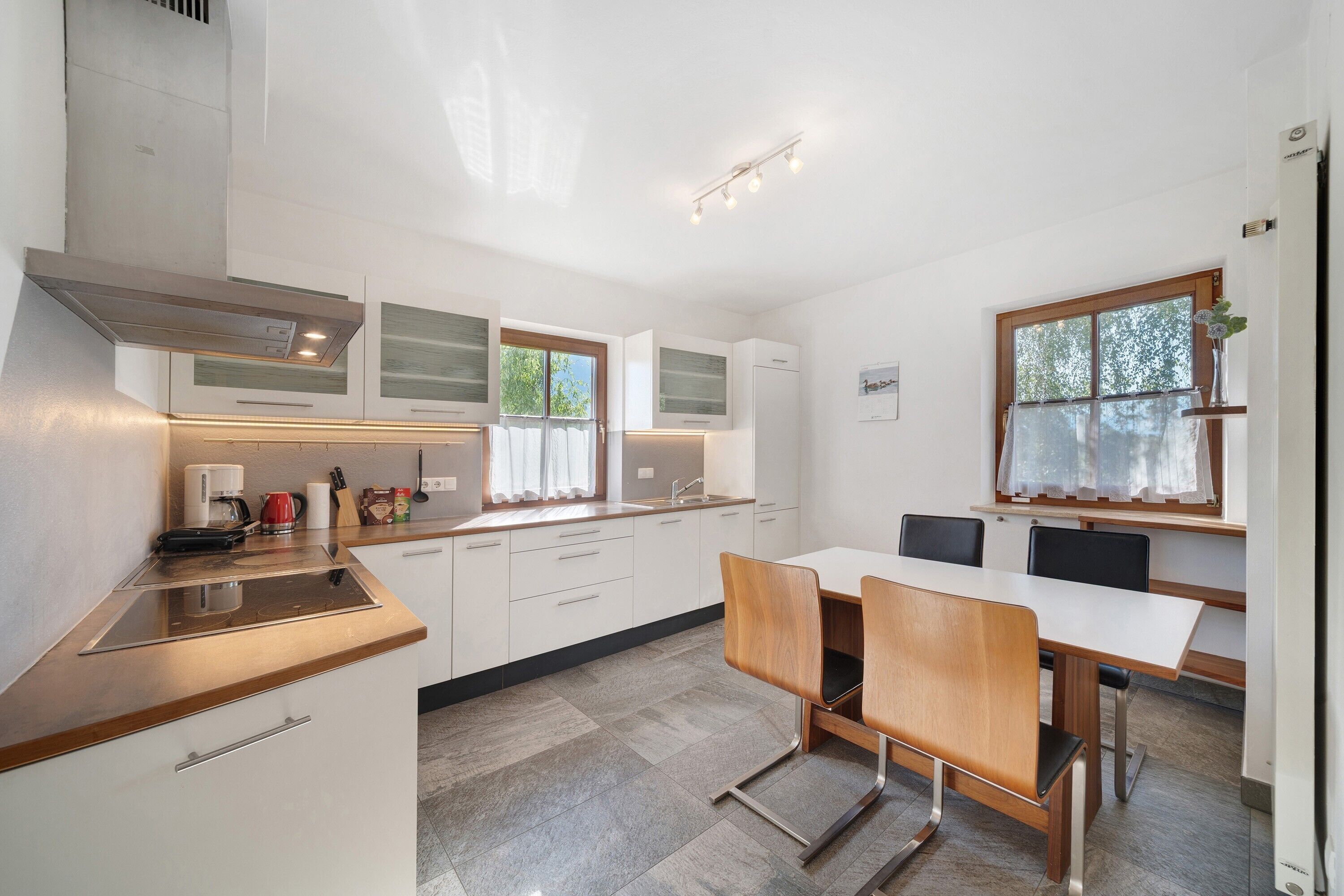 A modern kitchen with white cabinets, a wooden countertop, and a dining area with a table and chairs.