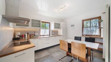 A modern kitchen with white cabinets, a wooden countertop, and a dining area with a table and chairs.