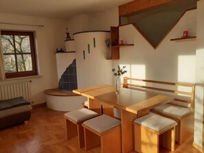 Una stanza accogliente con un tavolo in legno, sedute su panche, un termosifone, una finestra e una scala.