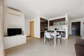 Una cocina moderna con armarios blancos, un microondas y un comedor con mesa y sillas blancas.