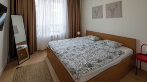 A bedroom with a bed, a mirror, a dresser, a red chair, and two wall-mounted deer head paintings. - Belgrade Waterfront Lux 2 (Belgrade)