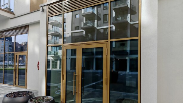 A modern building entrance with glass doors, a metal railing, and potted plants. - Belgrade Waterfront Lux 2 (Belgrade)