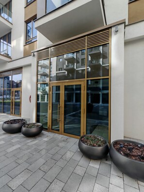 A modern building entrance with glass doors, a metal railing, and potted plants. - Belgrade Waterfront Lux 2 (Belgrade)