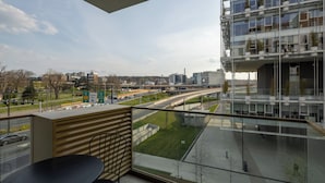 A balcony with a table and chairs, overlooking a highway and modern buildings. - Belgrade Waterfront Lux 2 (Belgrade)