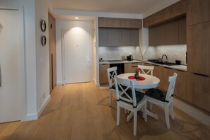 A modern kitchen with wooden cabinets, a dining table with chairs, and a small island. - Belgrade Waterfront Lux 2 (Belgrade)