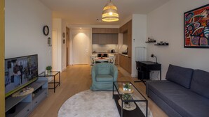A living room with a sofa, a coffee table, a TV, a dining area with chairs, and a kitchen in the background. - Belgrade Waterfront Lux 2 (Belgrade)