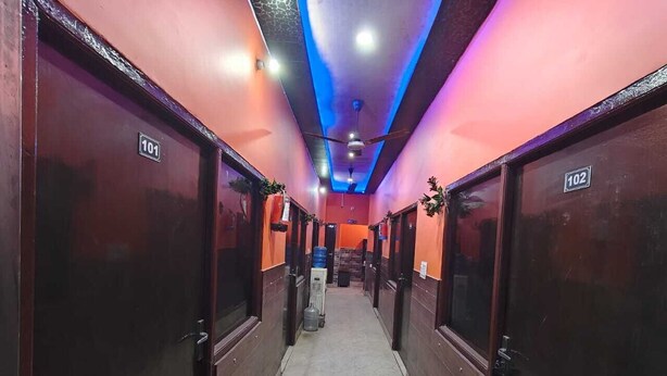 A hotel corridor with numbered doors, a ceiling fan, and a marble floor. - Deepak Guest House (Mathura)