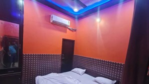 A room with an air conditioning unit, a bed with white bedding, and a door. - Deepak Guest House (Mathura)