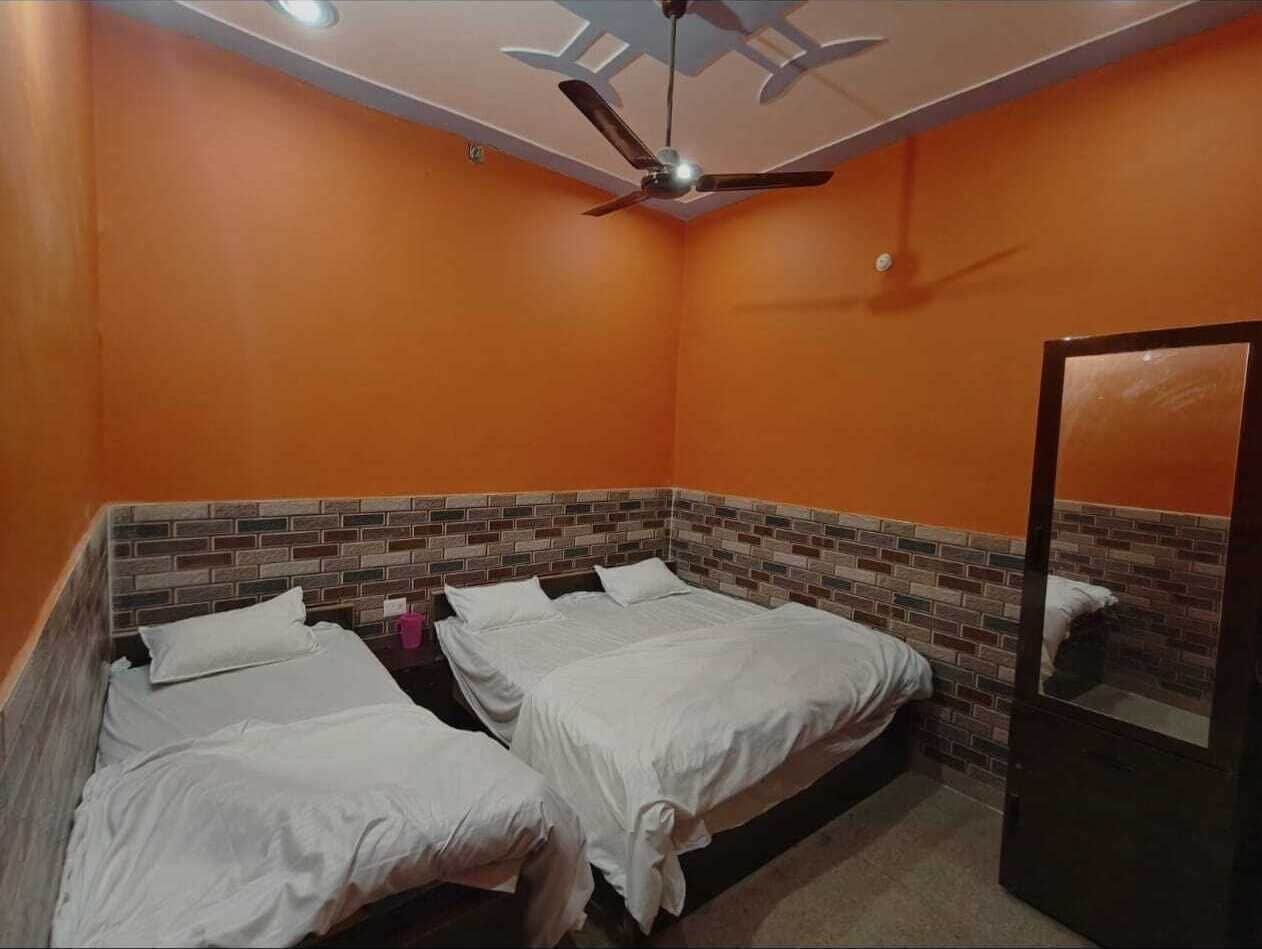 A room with three beds, a ceiling fan, and a mirror.