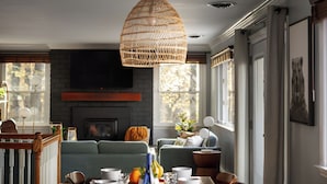 A dining area with a long table set for a meal, a hanging light fixture, and a sofa in the background. - Huckleberry Hills | Hot Tub & Fire Pit & Dogs (Harpers Ferry)