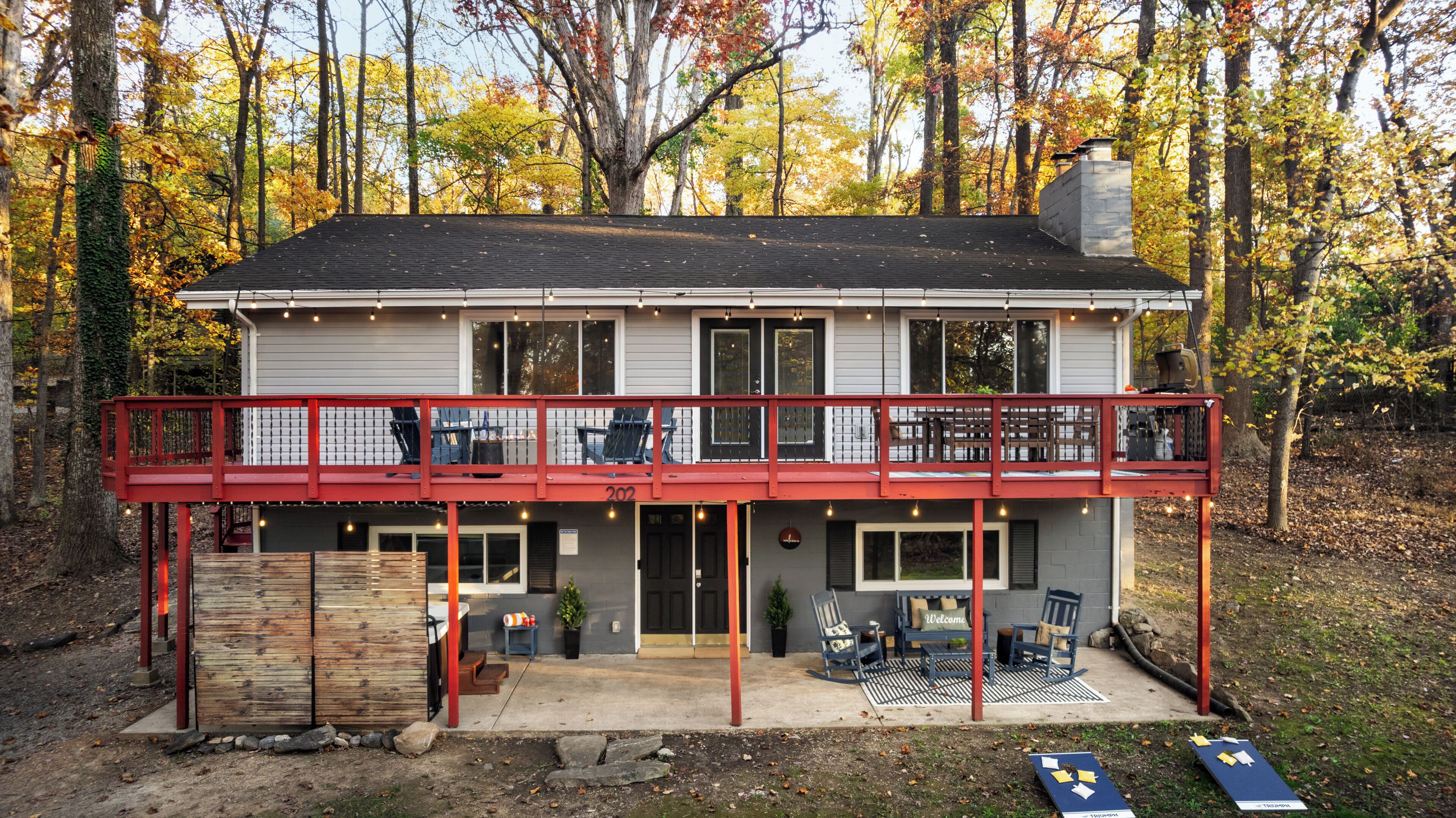 A two-story house with a covered front porch, a deck, and a chimney.