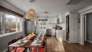 A modern kitchen with a dining area, white cabinetry, and a hanging light fixture. - Huckleberry Hills | Hot Tub & Fire Pit & Dogs (Harpers Ferry)