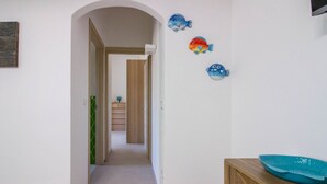 A hallway with a wooden cabinet and a blue bowl on top. - GuestHost - Cozy and bright 70 square meters apartment, perfect for four people, located on the first floor of a building without an elevator.The property enjoys an excellent location, in an extremely quiet area and just 250 meters from the seafront. Ame (Cannigione)