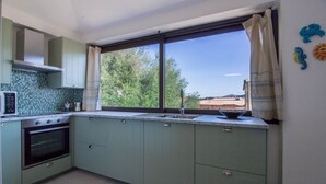 A kitchen with a large window, a built-in oven, and a sink. - GuestHost - Cozy and bright 70 square meters apartment, perfect for four people, located on the first floor of a building without an elevator.The property enjoys an excellent location, in an extremely quiet area and just 250 meters from the seafront. Ame (Cannigione)