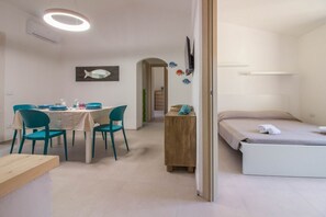 Ein Zimmer mit einem Bett, einem Tisch mit Stühlen, einem Fernseher und einer Fischdekoration an der Wand.
