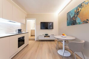 A modern kitchen with a built-in oven, a dining area with a round table and two chairs, and a flat-screen TV mounted on the wall. - Arco della Pace Sweet Home C by Halldis (Milan)