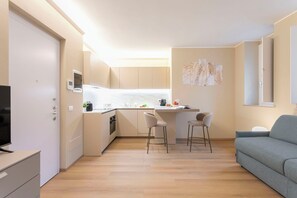 A compact living space with a kitchenette, a grey sofa, and a TV. - Arco della Pace Sweet Home D by Halldis (Milan)