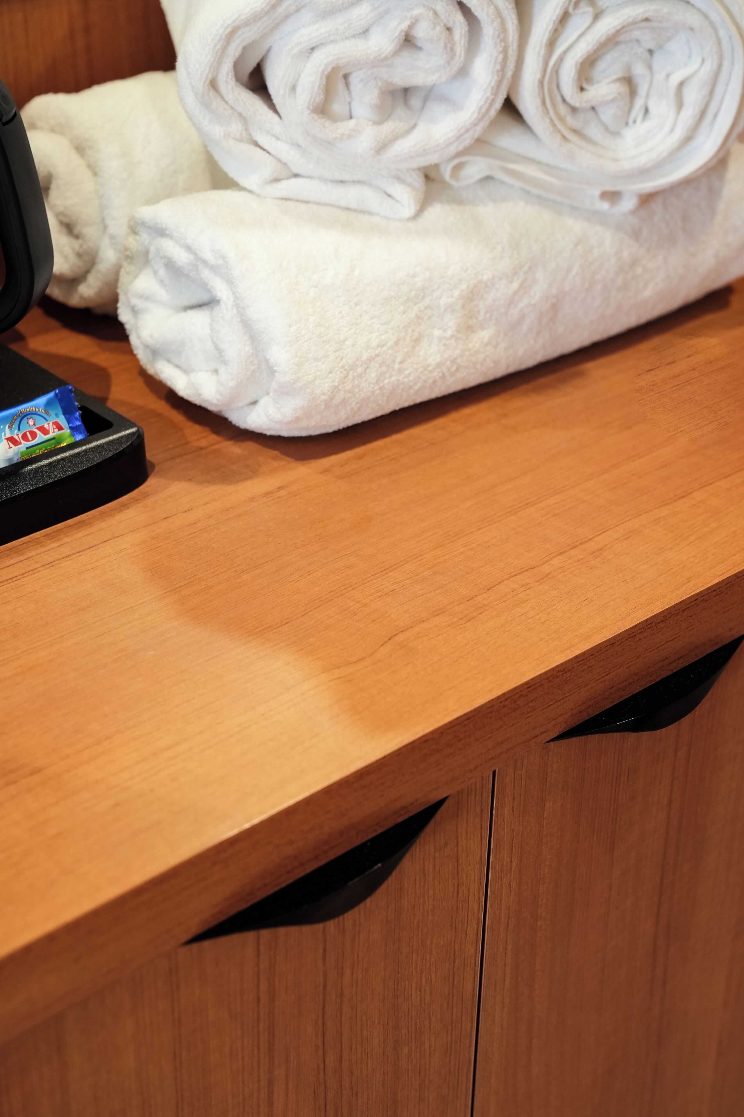 A wooden counter with folded white towels and a black object on it.