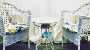 Two white wicker chairs with floral cushions, a small round table, and a plain white backdrop.