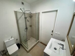 Une salle de bain avec une douche à parois de verre, des toilettes et un lavabo avec un miroir.