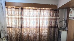 A bathroom with a marble sink, patterned curtains, and a visible electrical outlet.
