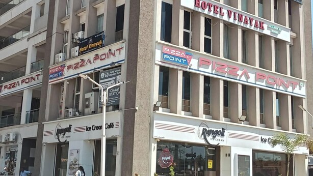 A multi-story building with a Pizza Point restaurant on the ground floor, a Hotel Vinayak on the second floor, and a Care Hospital on the top floor.