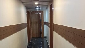 A corridor with a glossy black marble floor, white walls, and brown paneling.
