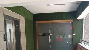 A hotel entrance with a check-in counter, a reception desk, and an elevator.