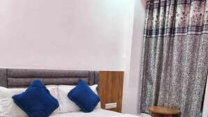 A bed with white and blue bedding, a wooden headboard, and a small round table beside it.