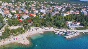 Ilmakuva rannikkokaupungista, jossa on ranta, kirkas sininen vesi ja asuinrakennuksia.