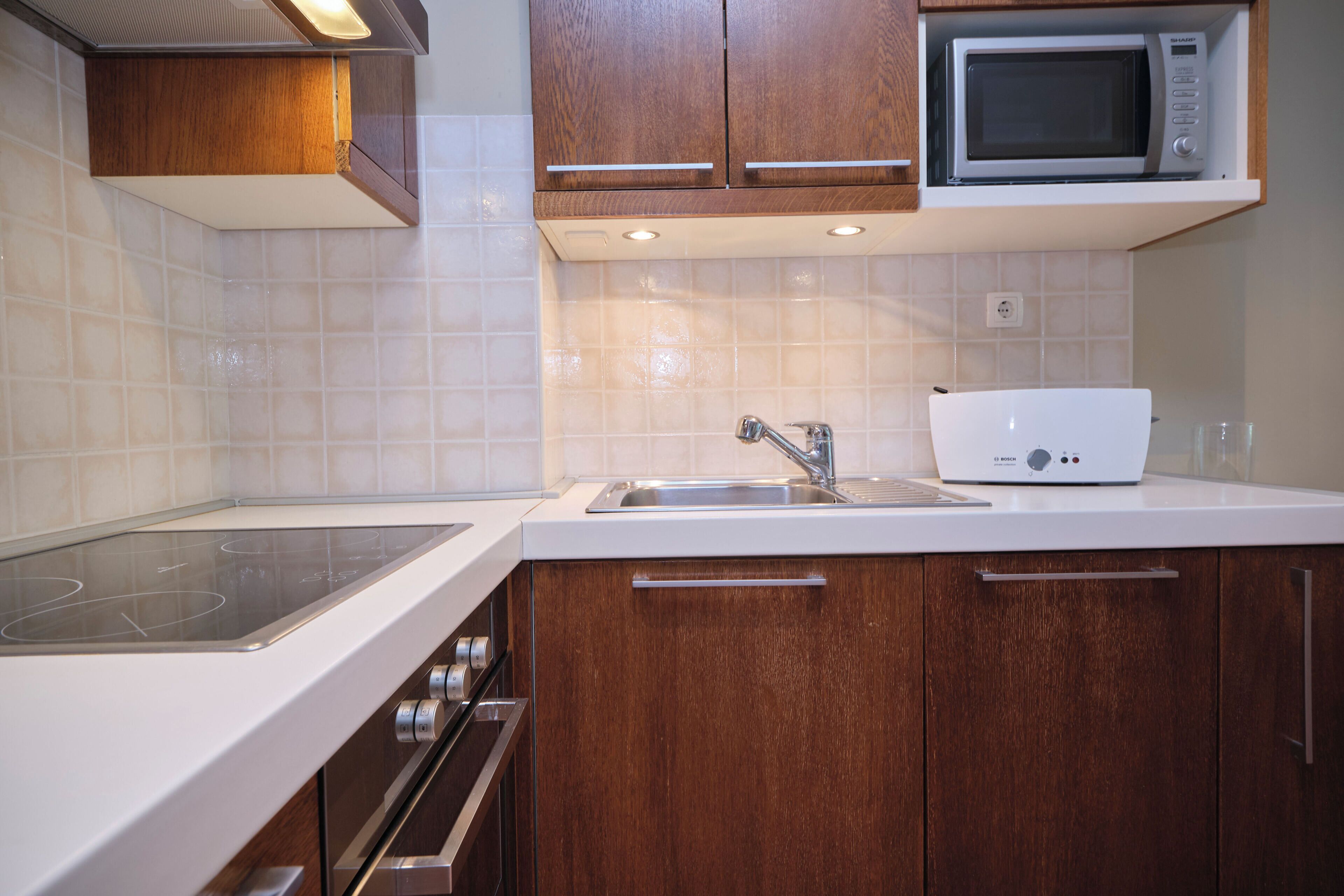 Une cuisine équipée d’un four à micro-ondes, d’une cuisinière, d’un évier et de meubles de rangement en bois.