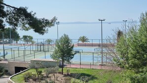 Tenniskenttä, jolta avautuu esteetön näkymä merelle ja kaukaisiin vuorille.
