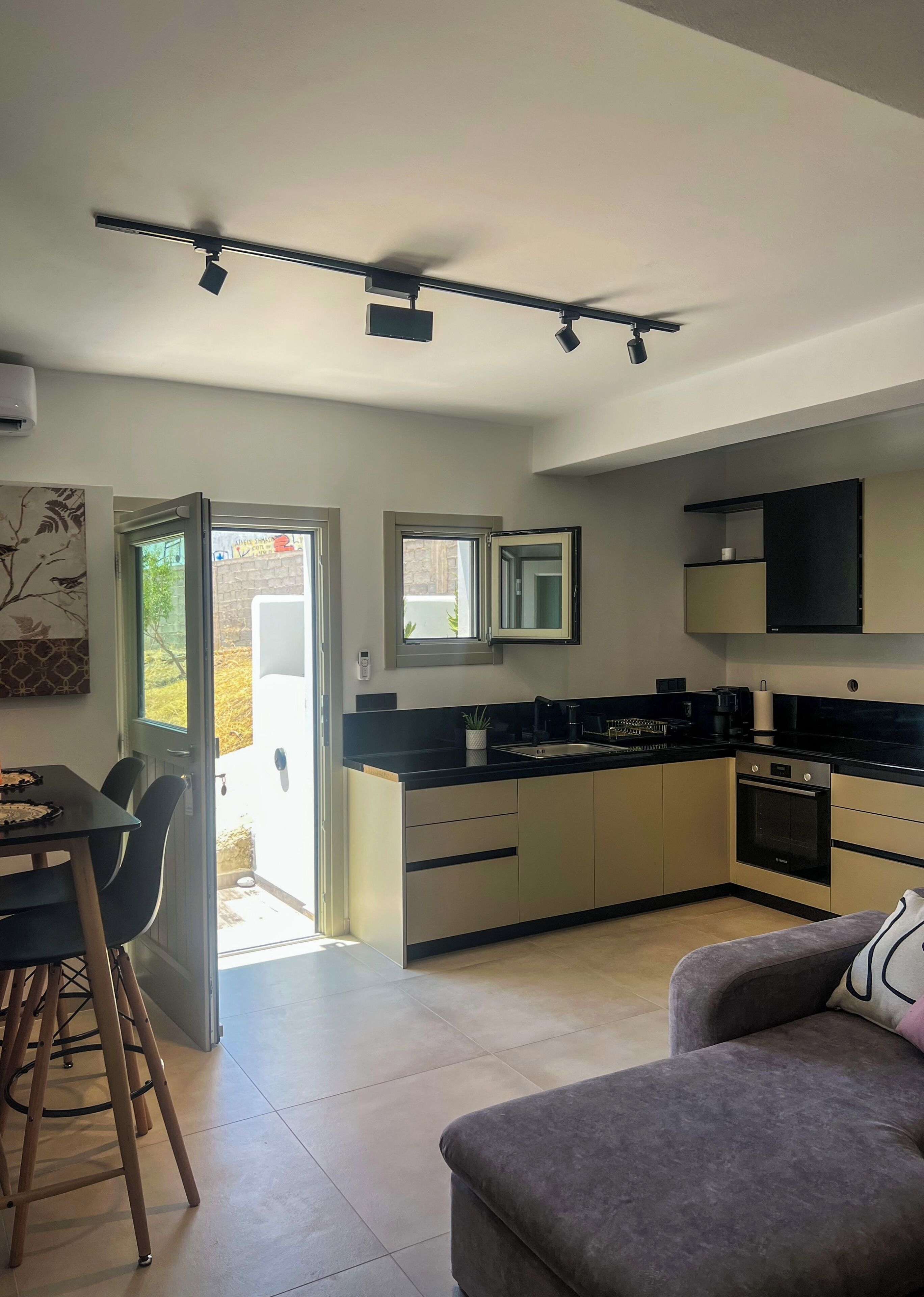 Una cocina moderna con comedor, sofá y vistas por la puerta abierta.