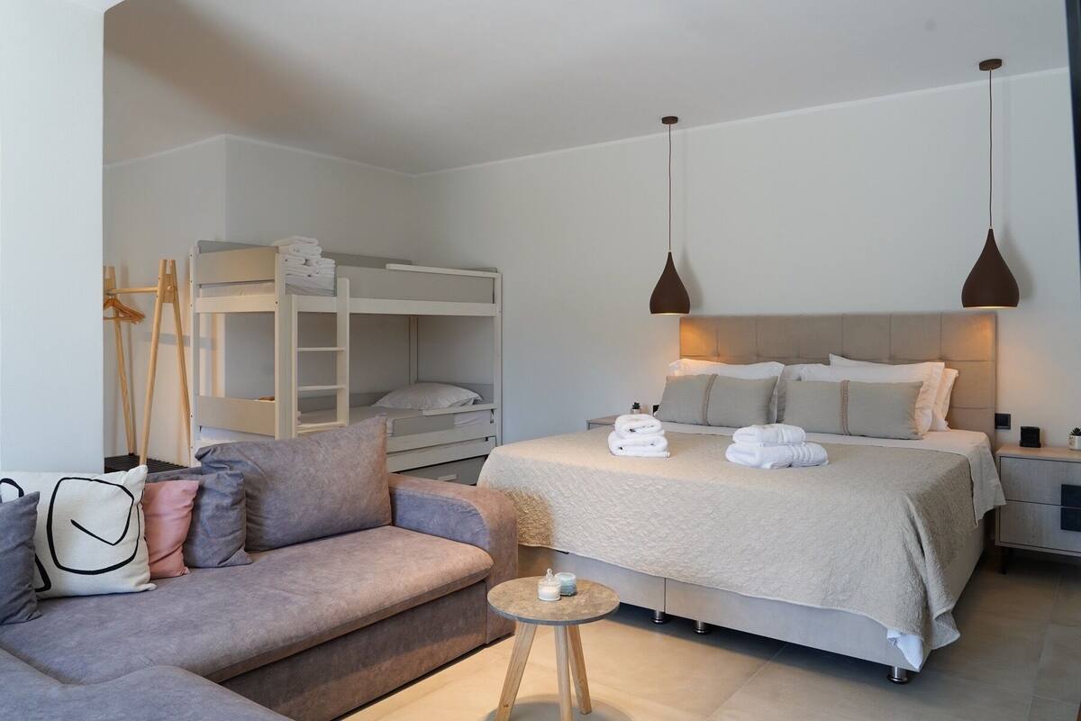 Ein modernes Schlafzimmer mit Etagenbetten, einer Schlafcouch, einem Nachttisch und Pendelleuchten.