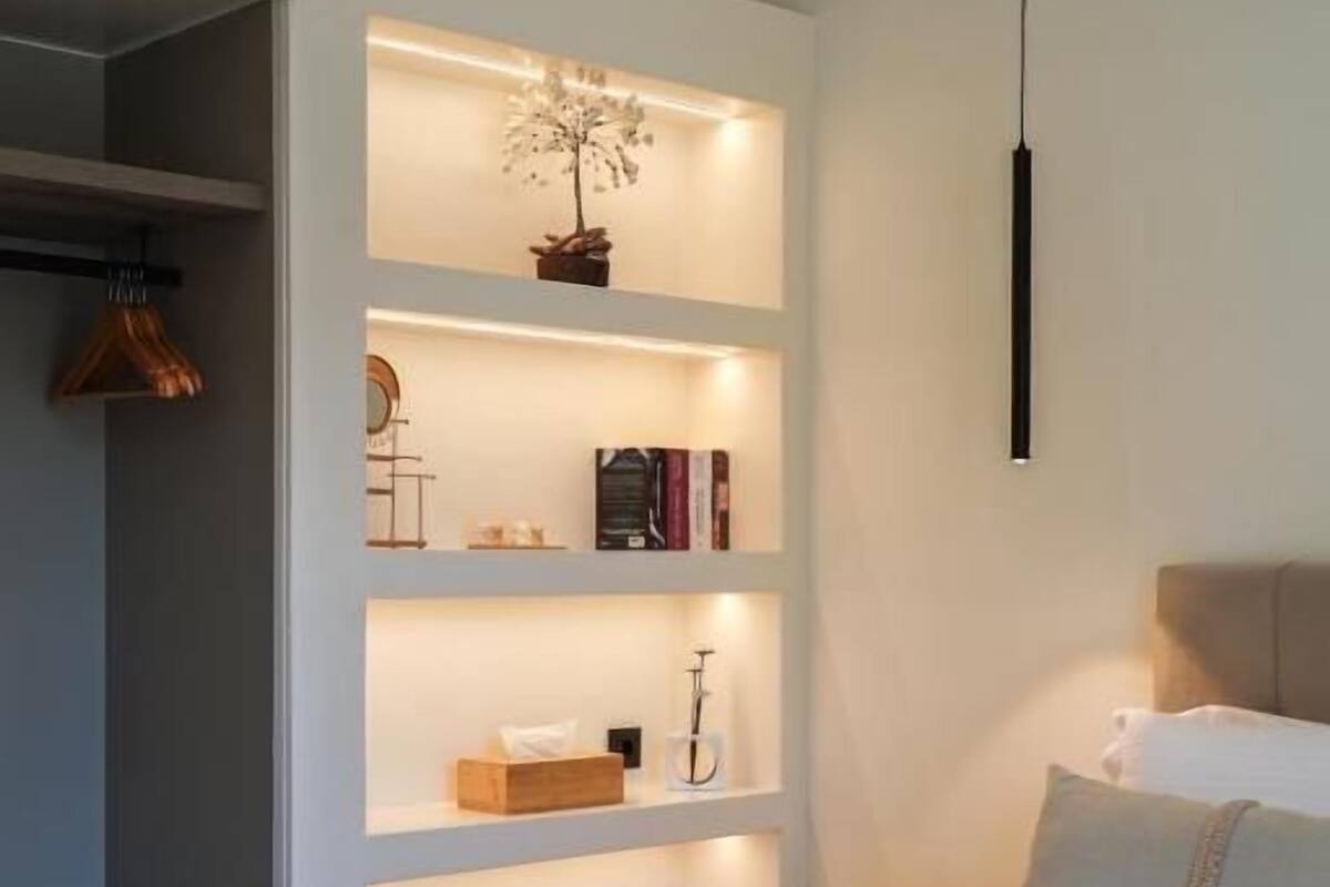 Ein Schlafzimmer mit einem Bett, einer Hängeleuchte und eingebauten Regalen mit Büchern und Dekoration.