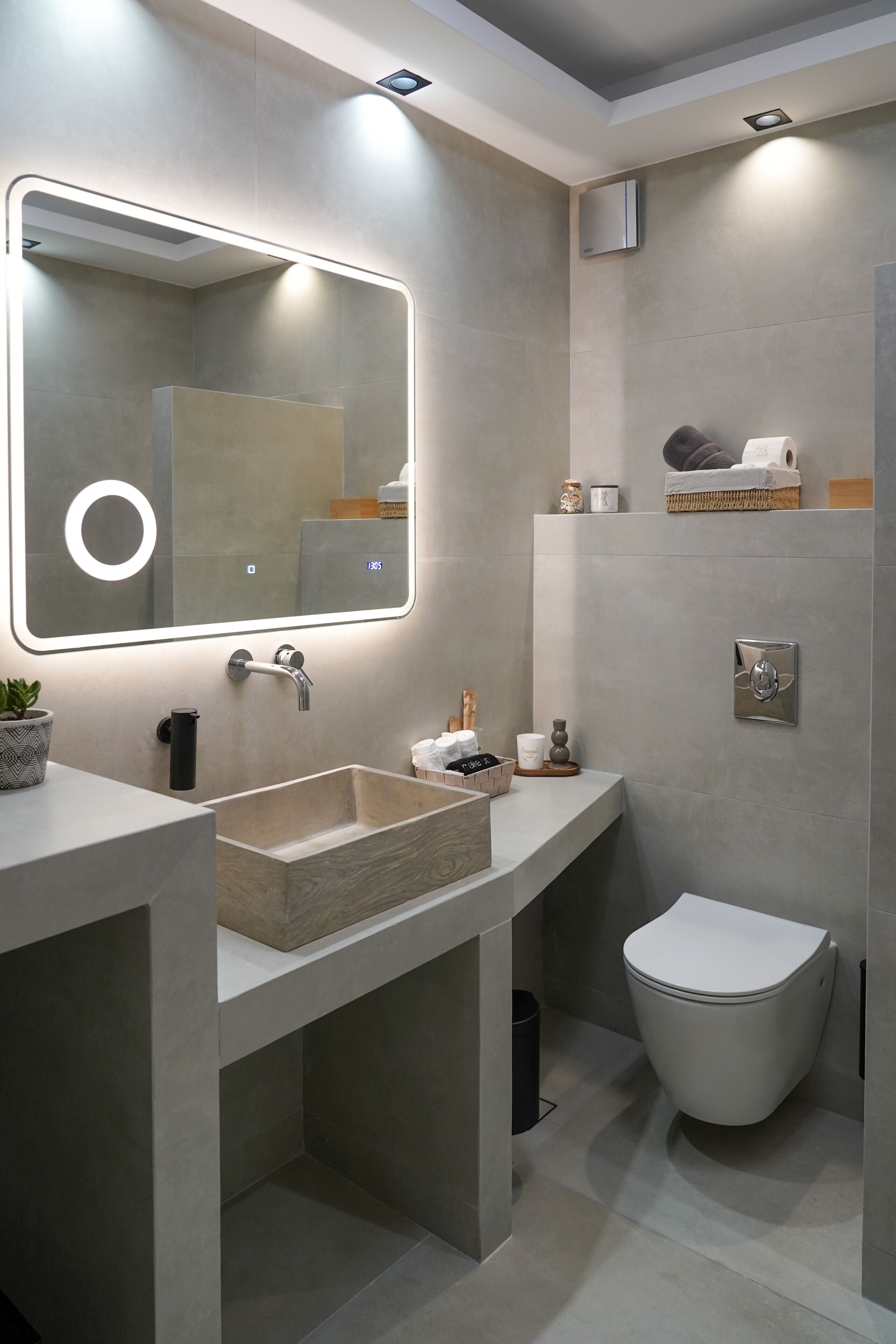 A modern bathroom with a large mirror, a sink, a toilet, and a shower area.