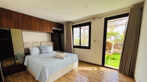 Ein Schlafzimmer mit einem Bett, einem großen Spiegel, einem Holzschrank und einer Glastür, die auf einen Balkon führt.