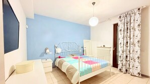 Un dormitorio con cama, mesita de noche, lámpara y cortinas.