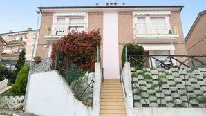 Un edificio residencial con una escalera central, un pequeño jardín de follaje rojo y una fachada de ladrillo.
