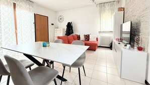 Una sala de estar moderna con una mesa de comedor, sofá y televisor.