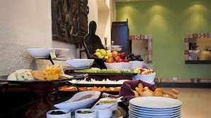 A buffet with various food items and a stack of plates. - African Regent Hotel (Accra)