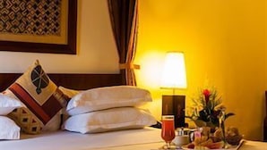 A hotel room with a neatly made bed, a tray with snacks and a drink, and a lamp on the nightstand. - African Regent Hotel (Accra)